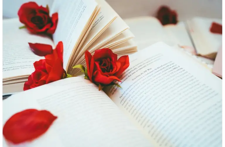 Valentine's Day themed reading with a romance novel open on a table with roses scattered
