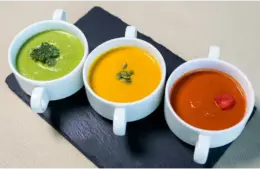 three different winter soups in white bowls