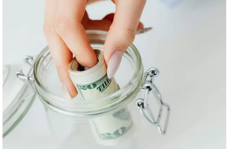 A person putting money in a jar promoting smart money habits