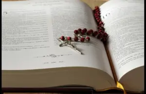 In daily devotion, a Bible is open with a red beaded necklace with cross inside.