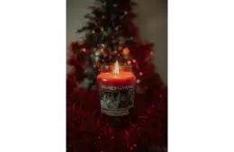 Photo of a red candle from Yankee Candle with a Christmas tree in the background