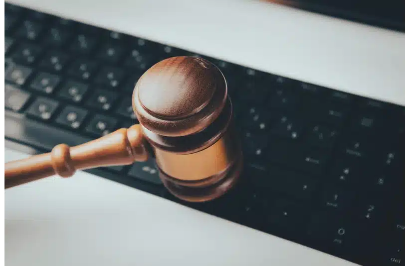 A wooden judge's gavel rests on a computer keyboard, symbolizing online justice or digital law. The image conveys a tone of authority in the digital realm. court, justice, lawsuit, legal