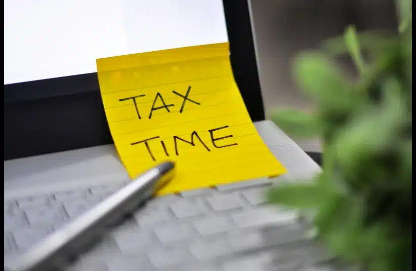 A beginner's guide to filing taxes, a computer with a sticky note that says tax time.