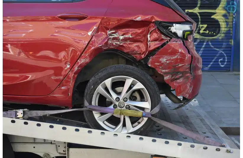 Image of a red car being towed/recovered which was involved in a road traffic collision.