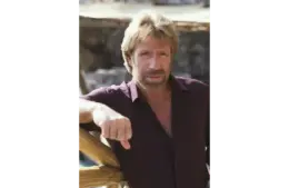 Image of Chuck Norris in a button down shirt with one arm propped up. He is squinting at the camera.