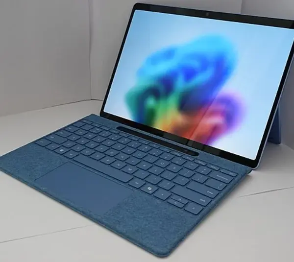 Microsoft Windows 11 Laptop. A sleek blue laptop with a detachable keyboard is open, displaying a vibrant, abstract, colorful wallpaper. It rests on a white surface, conveying a modern, tech-savvy tone.