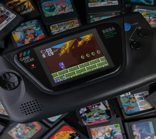 A pile of retro games on a table with a retro handheld game. Myrient