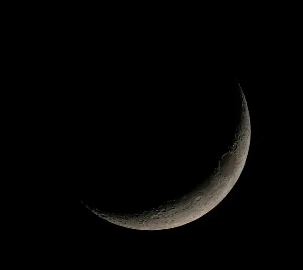 A crescent moon set against a black sky, showcasing detailed surface textures. The scene is serene and evokes a sense of calm and wonder.