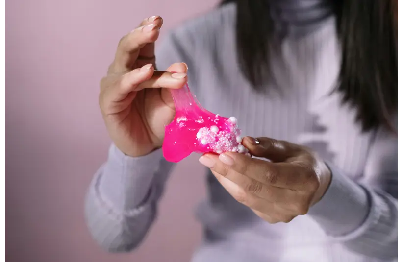A woman playing with pink slime.
