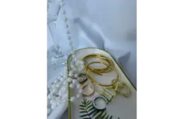 A tray with several gold and silver bangles, rings, and a string of white pearls on a white surface showing metallic accessories for everyday chic