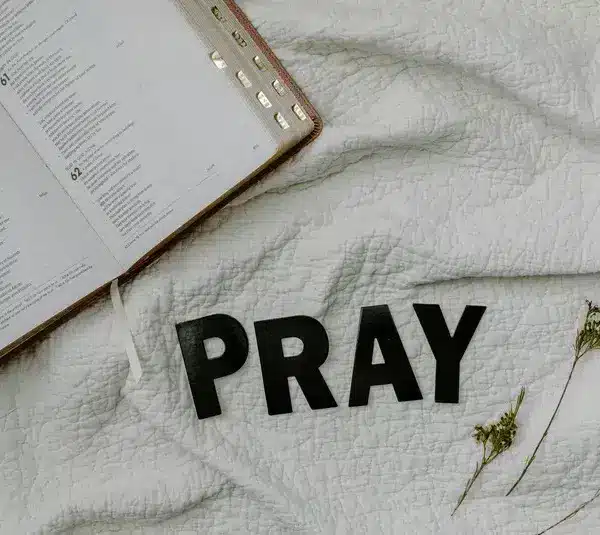 In daily devotion, a Bible is ope on white cloth background.