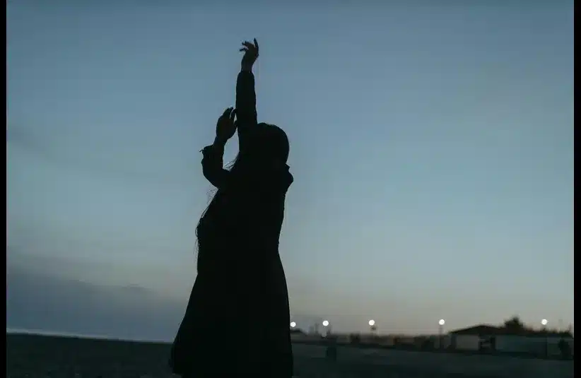 In daily devotion, woman lifts her hands.