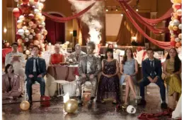 The cast of "Malcolm In The Middle: Life's Still Unfair" in formal wear sit disheveled in a decorated ballroom, surrounded by balloons and confetti, conveying a sense of chaos post-event.
