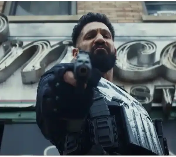 Frank Castle, The Punisher, with a stern expression, points a gun towards the camera, wearing tactical gear. He's set against an old, vintage restaurant sign. The mood is tense.