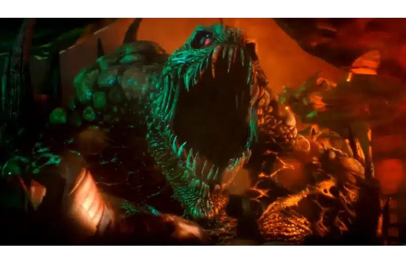 A menacing, large green monster with glowing eyes and sharp teeth is roaring fiercely in a fiery, orange-lit environment, conveying a sense of danger.