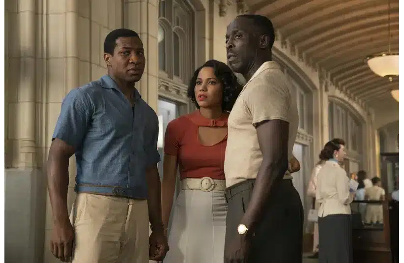 Lovecraft Country Scene of three people stand together in a vintage hallway; the atmosphere is tense. Two men face each other, and a woman looks on, concerned.