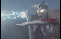 Ultraman, a silver and red robot-like figure, emits blue energy beams from its hand against a cloudy sky and mountain backdrop, conveying action and power.