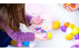 A little girl is opening her Easter eggs full of candy