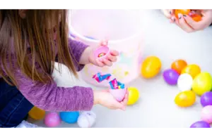 A little girl is opening her Easter eggs full of candy