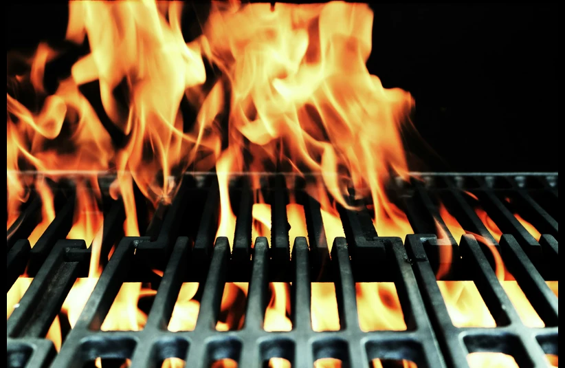 Close-up of a barbecue grill with bright, dancing flames above the metal grates. The vibrant fire conveys intense heat and energy, ready for grilling.