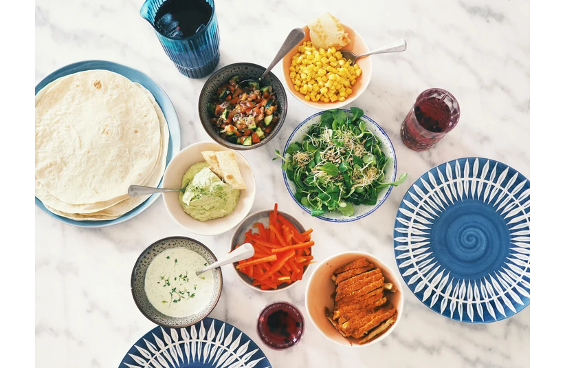 Assorted ingredients in separate bowls to assemble chicken tacos. 
