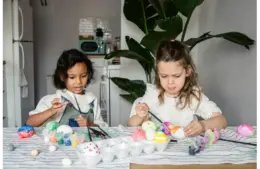 Two children dyeing Easter eggs