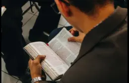 In daily devotional, a man is seen reading the Bible in a Bible perhaps in a study group.