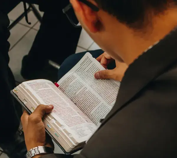 In daily devotional, a man is seen reading the Bible in a Bible perhaps in a study group.