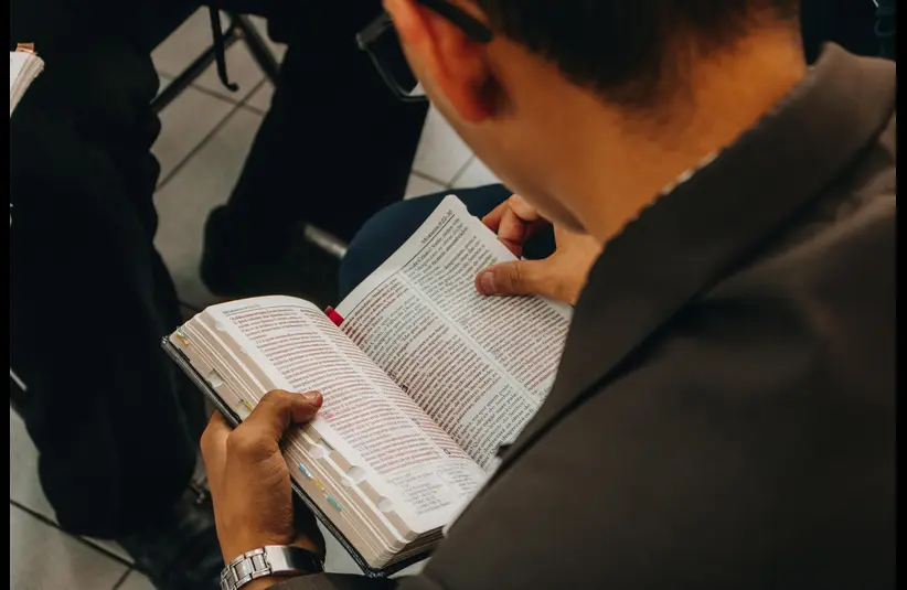In daily devotional, a man is seen reading the Bible in a Bible perhaps in a study group.