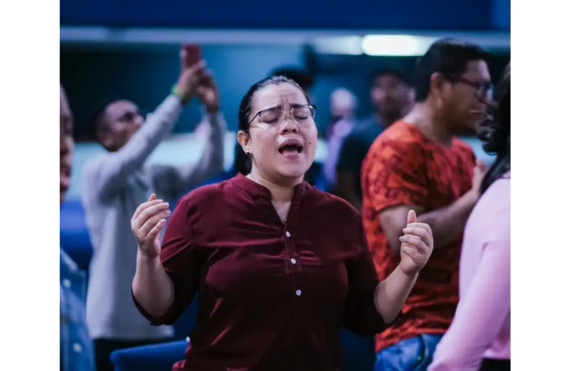 In daily devotion, a woman praises God in church.