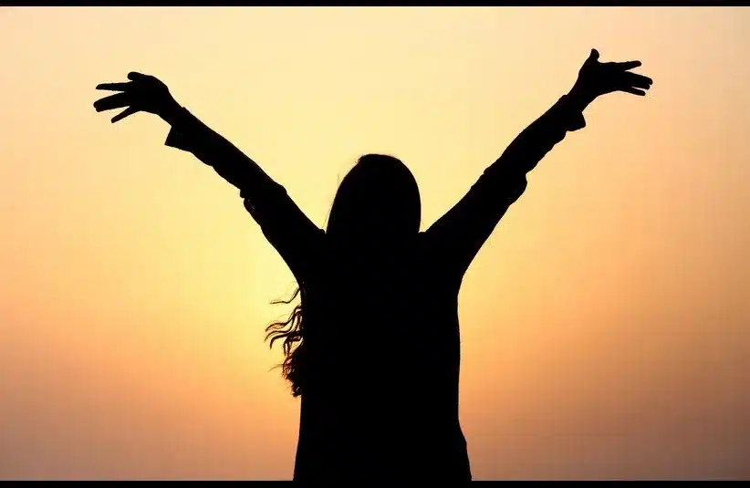 In daily devotion, a woman joyfully extends her arms.