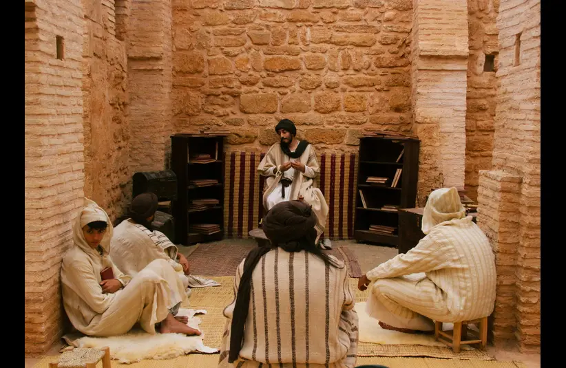 In the daily devotional, a religious leader teaches students in a small room.