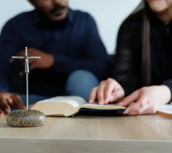 In the daily devotional, two people are studying the Bible. near a replica of the cross.