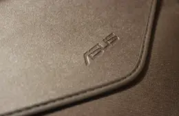 Close-up of a textured brown leather case with the "ASUS" logo embossed, conveying a sleek and professional appearance.