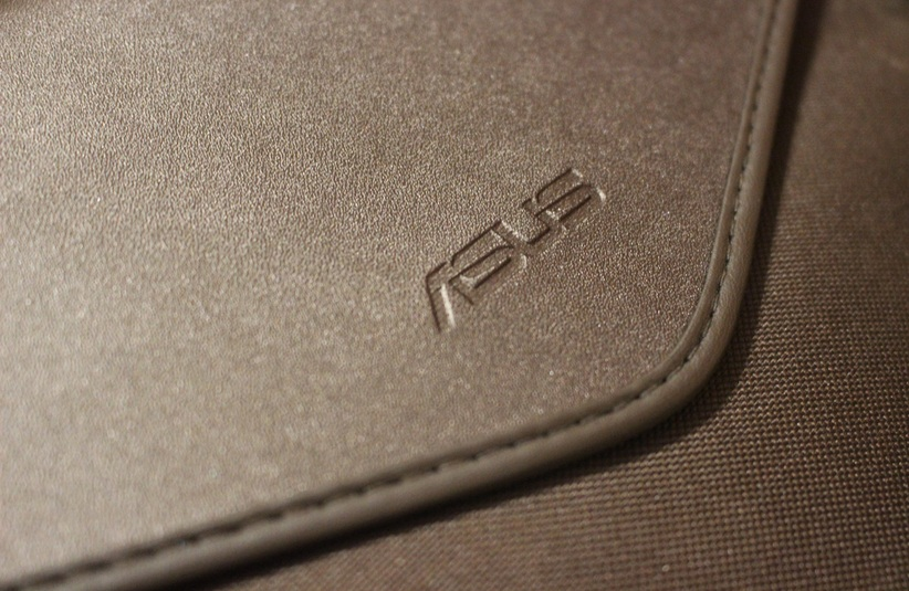Close-up of a textured brown leather case with the "ASUS" logo embossed, conveying a sleek and professional appearance.