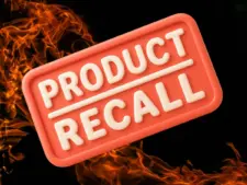 Red sign with bold white text "Product Recall" on a black background, surrounded by dynamic orange flames, conveying urgency and alertness.
