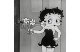 black and white shot of Bebby Boop in a black dress and holding flowers.