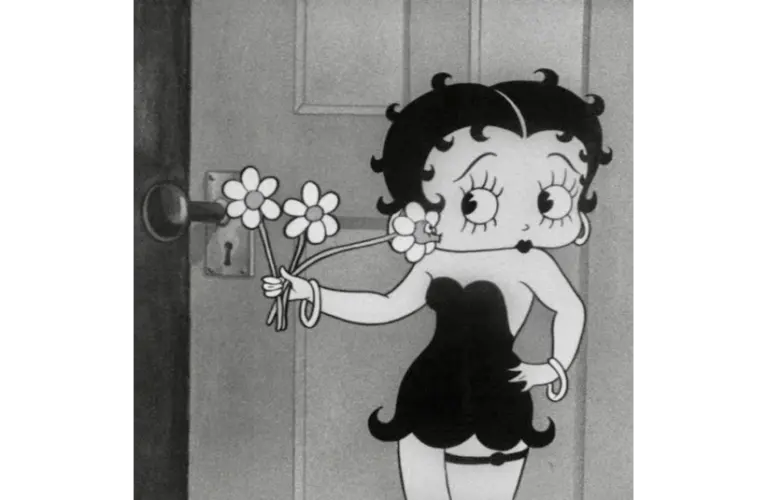 black and white shot of Bebby Boop in a black dress and holding flowers.