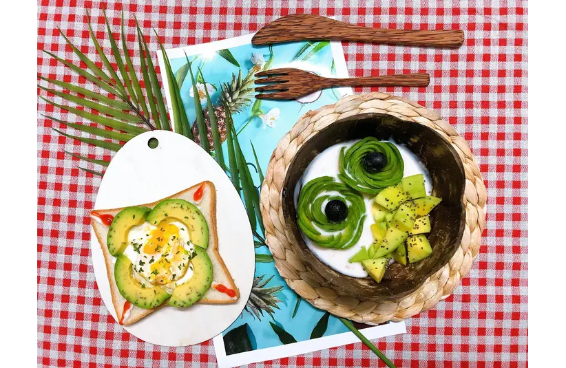 Top view of an artistic avocado creative breakfast on a checkered picnic blanket