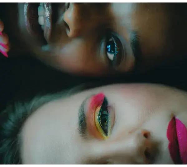 Intimate portrait of two women with bold makeup looks, showcasing diversity and beauty