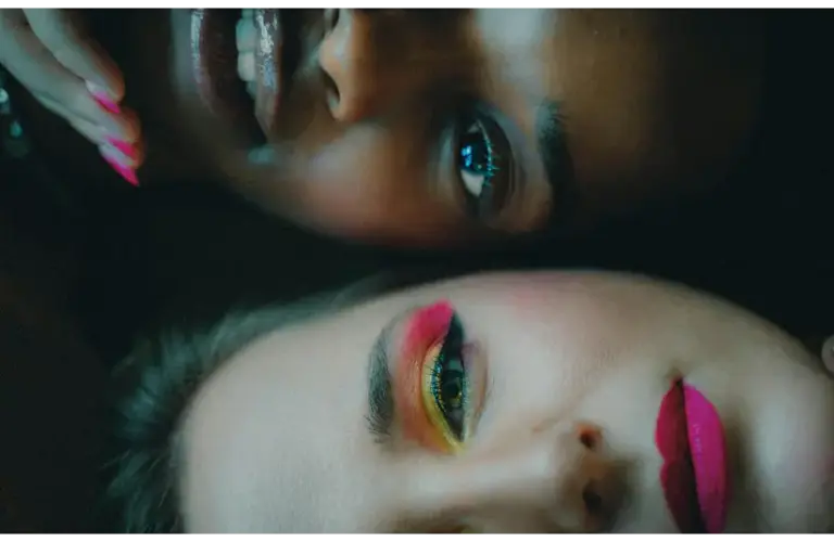 Intimate portrait of two women with bold makeup looks, showcasing diversity and beauty