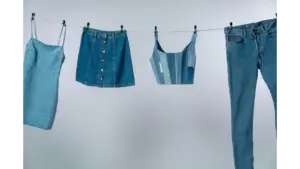 Various summer denim garments drying on a clothesline against a neutral background
