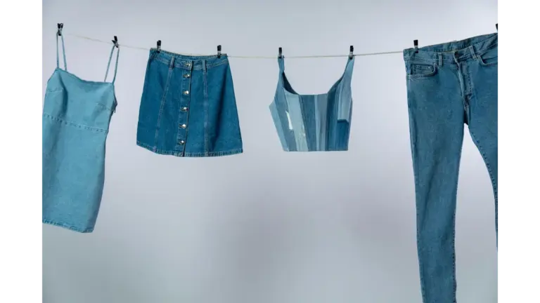 Various summer denim garments drying on a clothesline against a neutral background