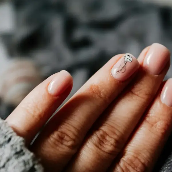 Close-up of a woman's elegant natural nails featuring a jellyfish design on soft pastel nails