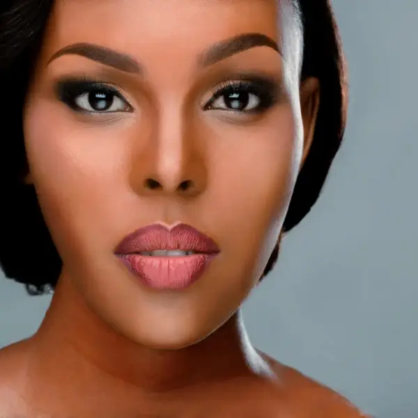 Close-up portrait of a woman with perfect makeup and expressive eyes showcasing the essence of sheer beauty on a smooth background.