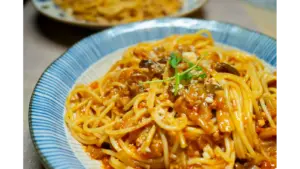 “Close‑up of a delicious spaghetti dish in tomato sauce with mushrooms and herbs, served in Tokyo, giving major pantry meals inspiration.”