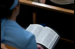 In this daily devotional, someone sits in a service with their Bible open.