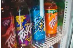 Close-up of assorted custom sodas bottled in a refrigerated grocery store display.