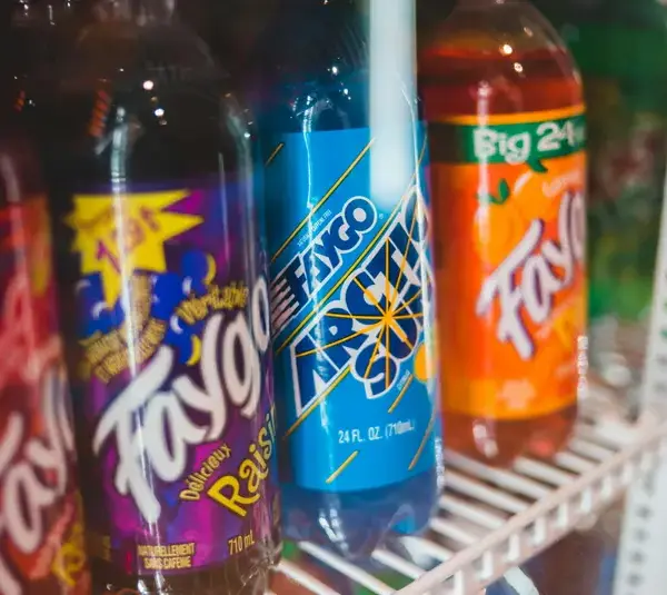 Close-up of assorted custom sodas bottled in a refrigerated grocery store display.