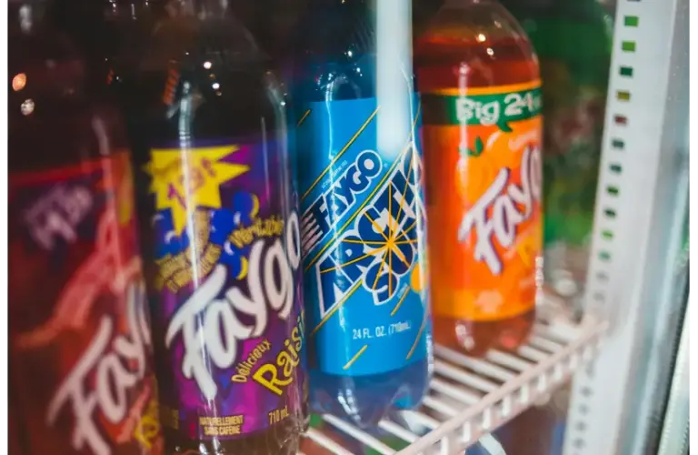 Close-up of assorted custom sodas bottled in a refrigerated grocery store display.